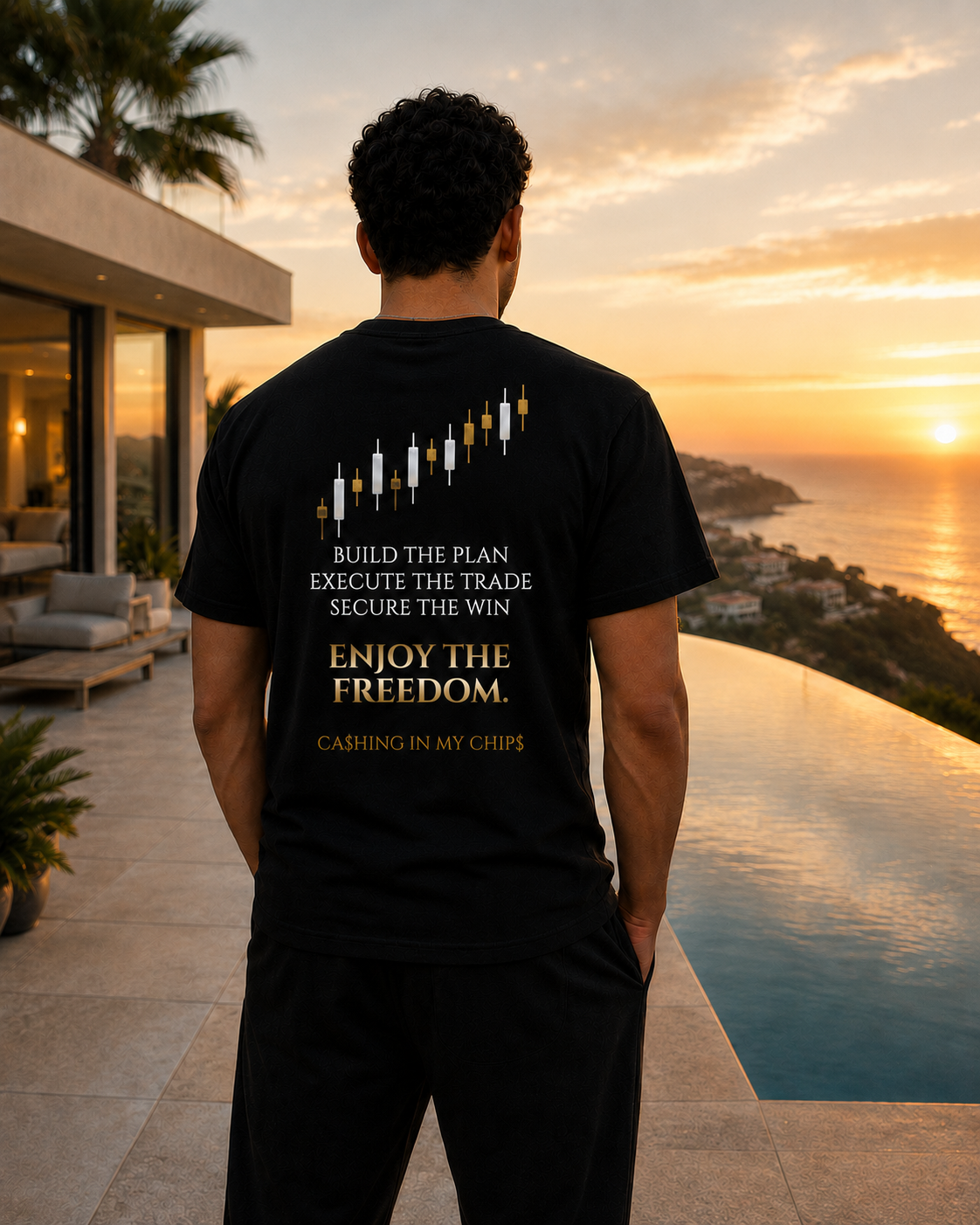 Man wearing the Ca$hing In My Chip$ “Enjoy The Freedom” trading lifestyle T-shirt while overlooking a luxury coastal villa and infinity pool at sunset.