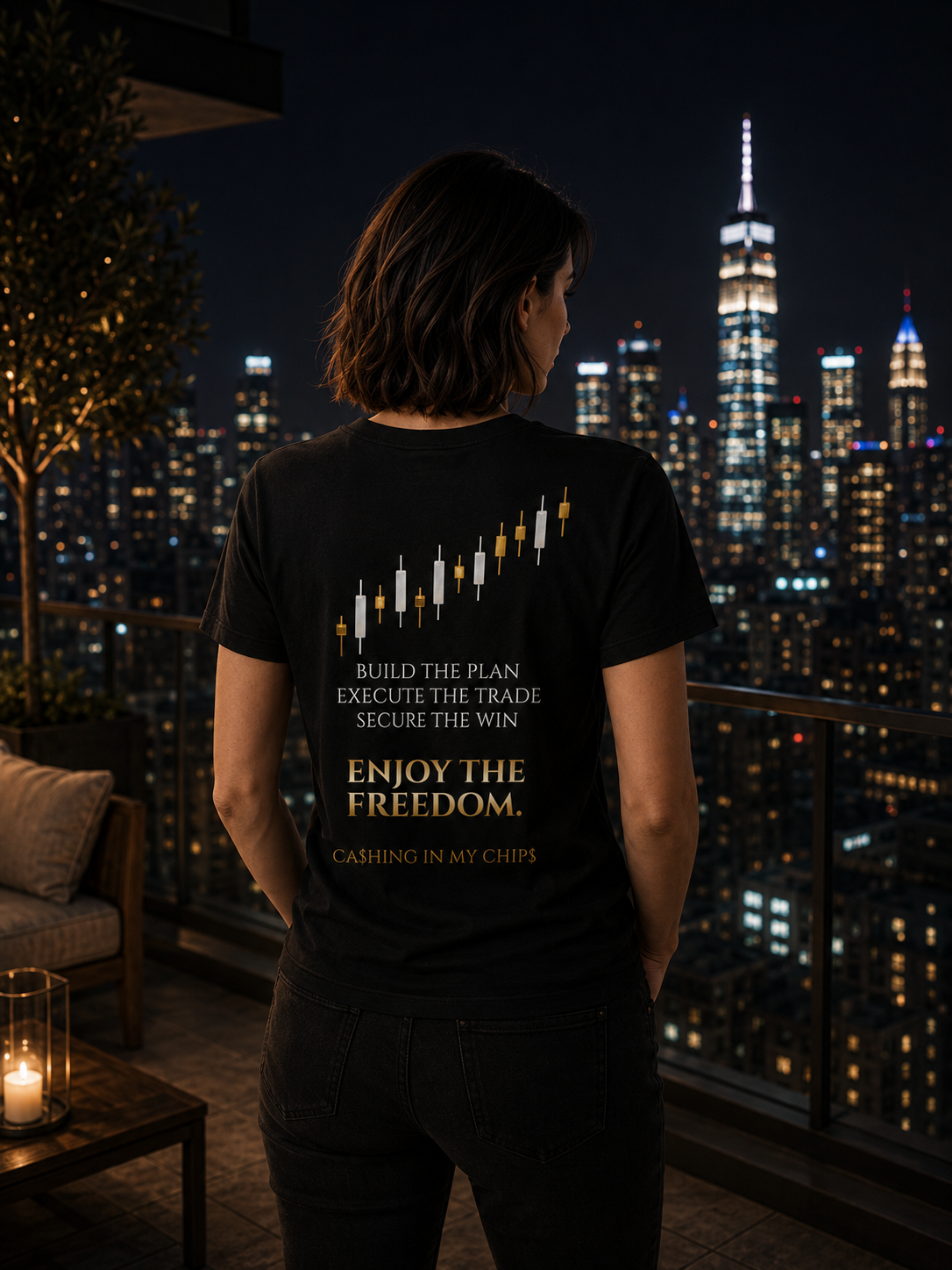 Woman wearing the Ca$hing In My Chip$ “Enjoy The Freedom” trading lifestyle T-shirt while overlooking a luxury city skyline from a rooftop balcony at night.